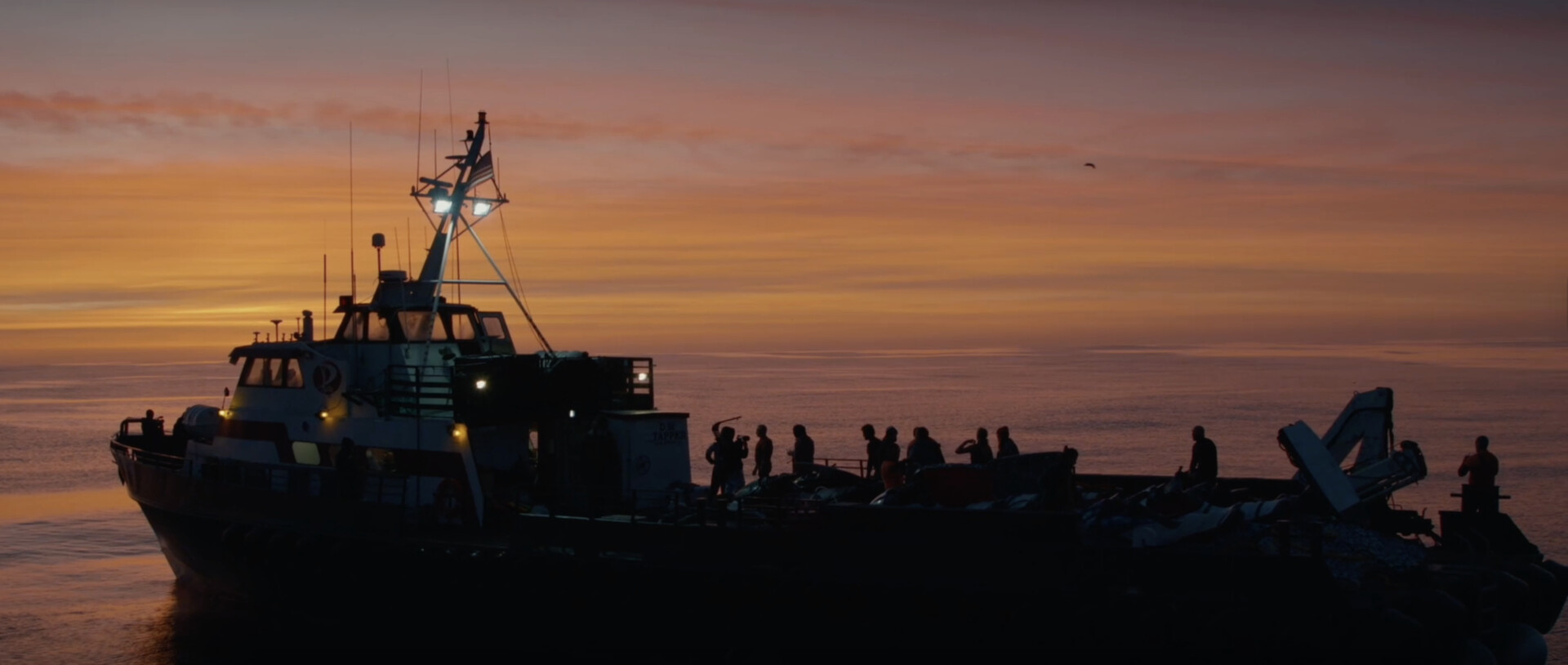 surfers on the back of a large boat at sunset