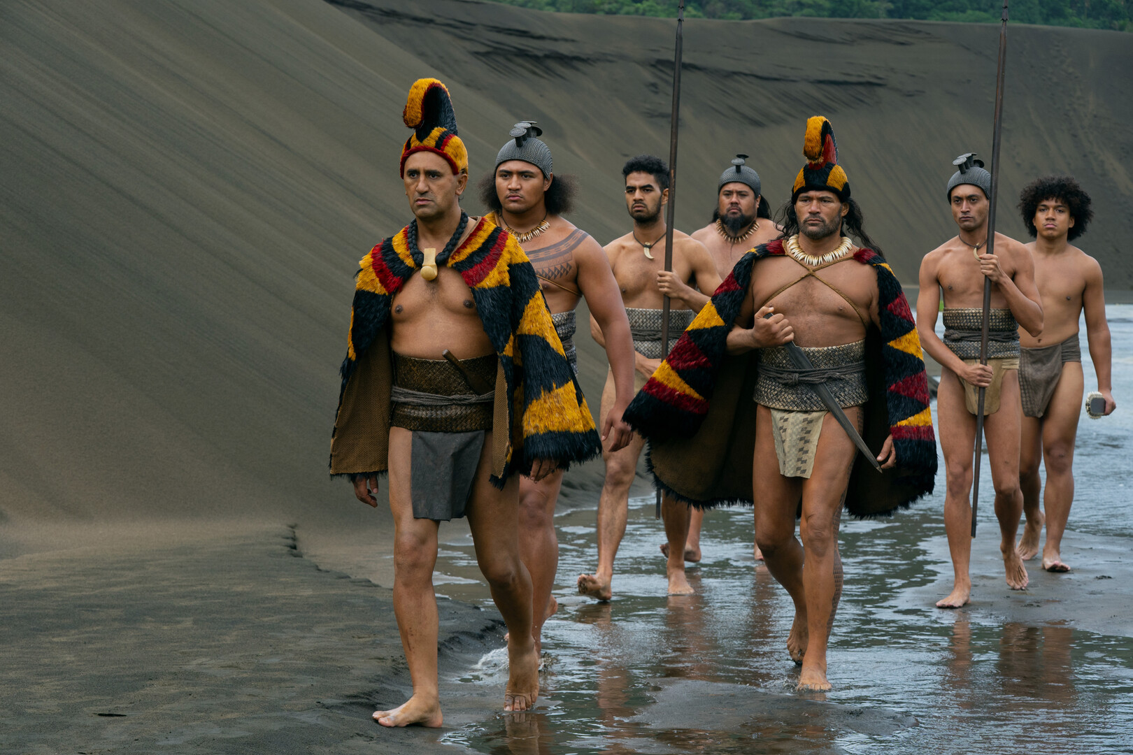 tribal leaders walking over volcanic sand